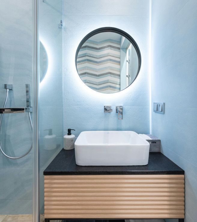 Swansea bathroom sink with blue tiled backsplash and mirror above.